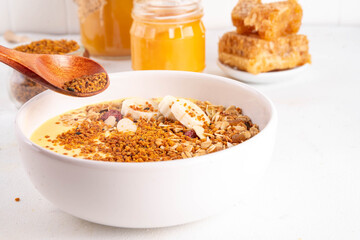 Healthy superfood fruit smoothie bowl with bee pollen, golden creamy shake or smoothie, with granola and banana. Clean eating, dieting vegetarian dish with bee pollen superfood organic powder 