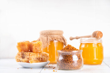 Bee pollen jar and spoon with honey and honeycomb. Trendy superfood, antioxidant organic powder, on white table background copy space