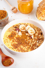 Healthy superfood fruit smoothie bowl with bee pollen, golden creamy shake or smoothie, with granola and banana. Clean eating, dieting vegetarian dish with bee pollen superfood organic powder 