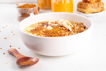 Healthy superfood fruit smoothie bowl with bee pollen, golden creamy shake or smoothie, with granola and banana. Clean eating, dieting vegetarian dish with bee pollen superfood organic powder 