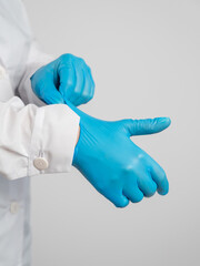 The doctor puts on latex gloves on a white background. 