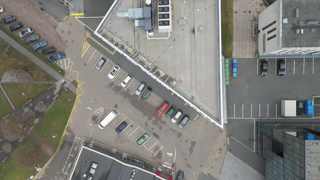 Drone revealing buildings with ventilation system on the rooftops and parked cars down below