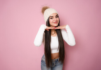 Photo of attractive brunette young woman wearing winter hat standing isolated over pink background