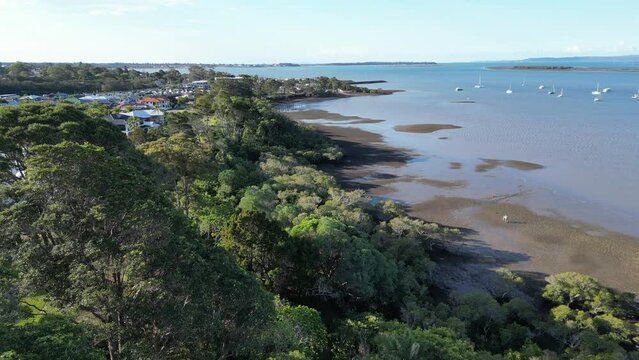 Drone of greenery by the sea and houses in Redland Bay with harbor in the background in Australia