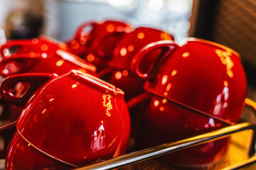 Many ceramic red coffee cups on a coffee machine shelf in a cafe. Selective focus. Red coffee cups on a shelf in a cafe, second row of selective red cup with soft focus.