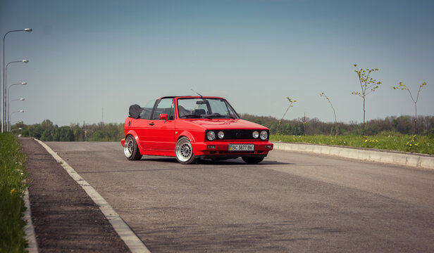 Red Volkswagen Golf mk2 cabriolet stationary on a rural road. Three quarter front view of red car diagonally parked. Lviv, Ukraine - May 02 2014.