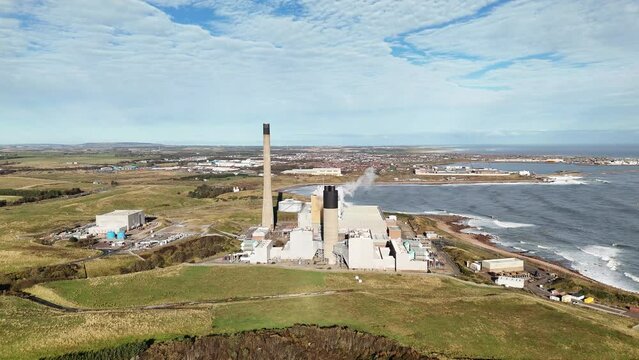 Shot of Peterhead Power Station with steam emanating from it and the sea in the background.