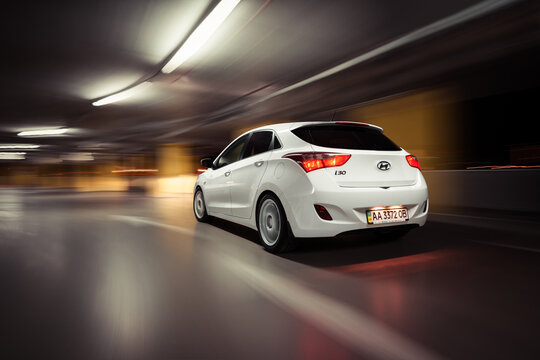 White Hyundai i30 driving inside parking garage. Motion shot of korean compact hatchback in urban setting. Kyiv, Ukraine - May 08 2014.