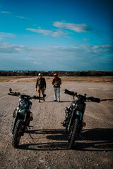 Fototapeta premium three people walk down an empty runway with several motorcycles parked in front of them