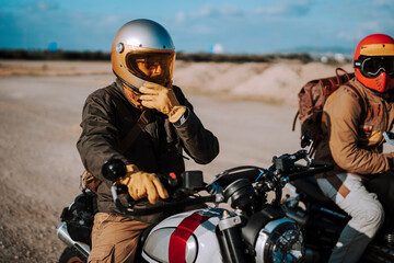 two men wearing helmets and jackets are sitting on a motorcycle