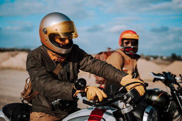 two people riding motorcycles in the desert near each other and wearing protective gear