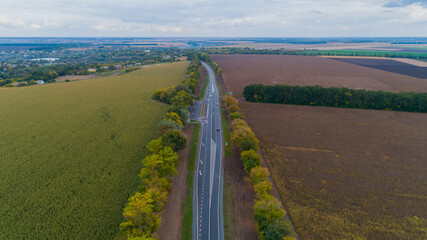 Aerial view new asphalt road in autumn on a cloudy day, road markings. Drone shot beautiful nature...