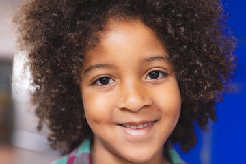 In school, young biracial boy with curly hair is smiling