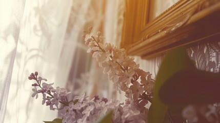   A close-up photo of a windowsill with blooms in the foreground and a vase adorned with flowers in the backdrop