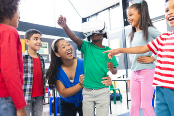 Obraz premium In school, in the classroom, a diverse group of students and their teacher are enjoying VR