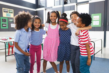 In school, diverse group of young students is hugging and laughing together in the classroom