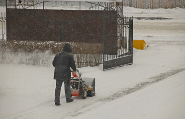Robotnik clears snow from the sidewalk with a manual snowplow driven by a gasoline engine. Fighting...