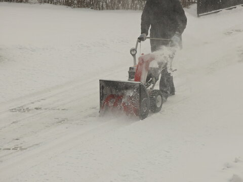 Robotnik clears snow from the sidewalk with a manual snowplow driven by a gasoline engine. Fighting the after-effects of a snowstorm. The power of the winter element