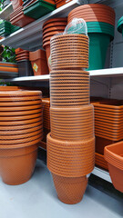 Stacked terracotta and green plastic plant pots on display shelves in a garden store