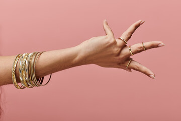indian woman showcasing gold bangles on her hand in a stylish pose.