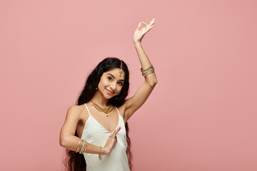 Graceful indian woman in white dress dancing on vibrant pink backdrop.