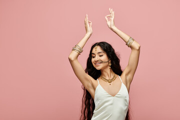 indian woman in white dress dances on pink background.