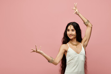 Young indian woman in white dress strikes a pose on vibrant pink background.