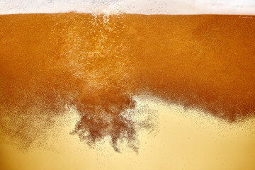Cold refreshing beer poured into chilled glass, creating cascade of bubbles and creamy head of...