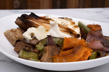 Vegetarian cuisine. Gourmet salad. Top view of a grilled vegetables salad with Italian burrata cheese on a white bowl.	