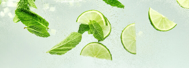Banner. Essence of summer. Lime slices and mint leaves adding cool and flavorful twist to glass of...