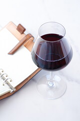 赤ワインを飲みながら、リング式のシステム手帳に日記をつける
