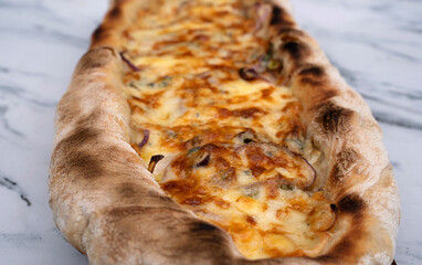 Gourmet cuisine. Closeup view of a homemade mozzarella, provolone, blue cheese and onion pizza on the white marble table.	
