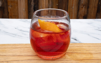 Drinks. Closeup view of a Negroni cocktail with gin, campari, red vermouth, ice and orange peel in a glass.	
