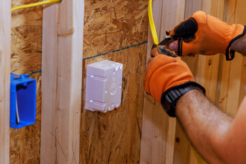 When new building is being constructed, an electrician connects wires to socket box