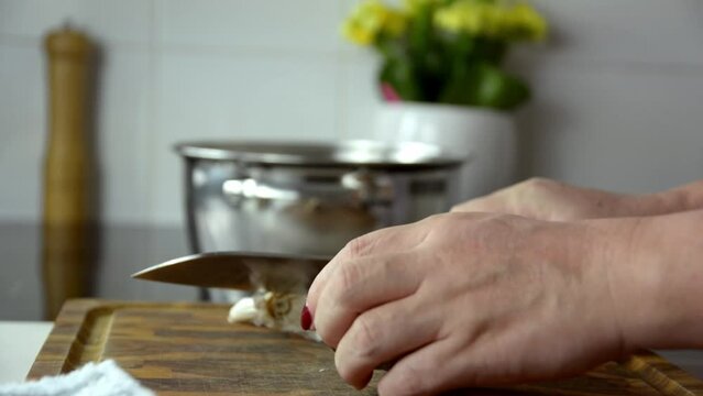 hands of a person peeling and chopping garlic at home