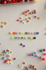 Making friendship bracelets with letter beads. Jewelry making supplies on the table. Flat lay.