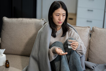Young woman holding medicine and glass of water, feeling sick, health care concept.