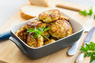 fried meat cutlets in a ceramic form on a wooden table