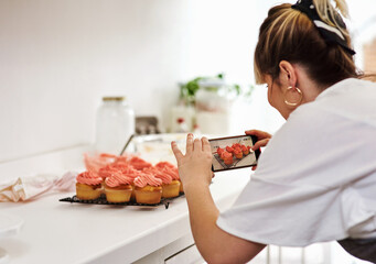Baker, woman and picture of cupcake in kitchen for social media, sweets and post on phone blog in...