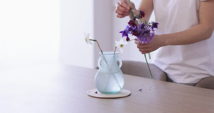 female hand picks up a flower in a vase at home