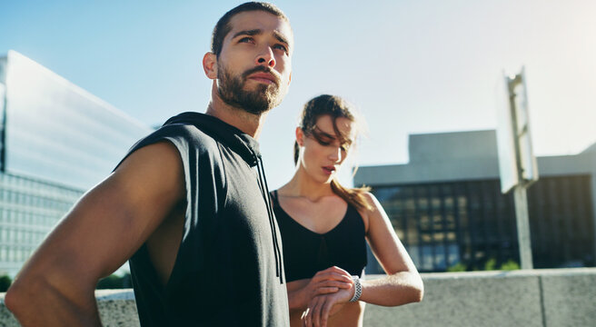 Couple, thinking and training time for performance in city, exercise or workout for race competition. Healthy man and woman with rest in urban town, watch and cardio fitness for outdoors running