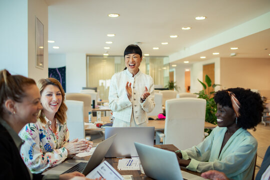 Multiethnic female colleagues discussing work with laptops in a modern office