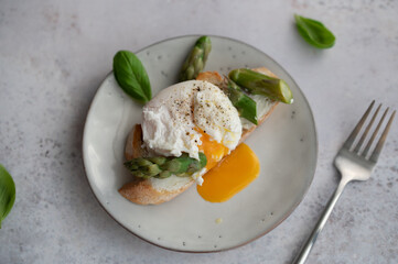 Toast bruschetta with grilled asparagus, poached egg and fresh cream cheese. Sourdough bread with vegetables and egg. Food photography. Healthy summer breakfast, brunch.