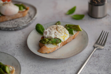 Toast bruschetta with grilled asparagus, poached egg and fresh cream cheese. Sourdough bread with vegetables and egg. Food photography. Healthy summer breakfast, brunch.
