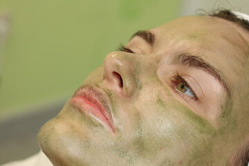 Naklejka premium Woman in cosmetologyst's cabinet. The office of a beautician applying a mask to a woman's face in a spa salon, view above. Aesthetic procedure. Care mask for facial skin. Face massage