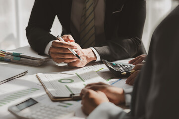 team of marketing is meeting about company finance, an employee is using calculator to calculate business profit of this year and show to head of department, planning about the best way to work