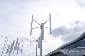 Array of vertical wind turbines against a cloudy sky, illustrating innovation in urban energy...