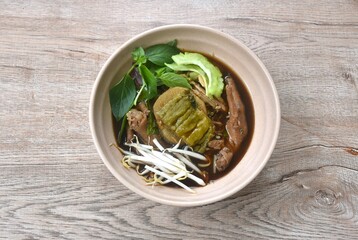 boiled chicken meat and feet with bean sprout in herb brown soup topping fresh bitter cucumber on bowl