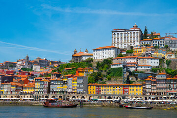 Cityscape of Porto (Oporto) over Douro River during a sunny day, Portugal. View of downtown Ribeira and embankment of Porto. Promenade view with colorful houses.