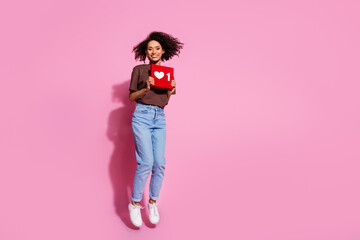 Full length photo of lovely young lady jump hold heart icon dressed stylish brown garment isolated on pink color background © deagreez